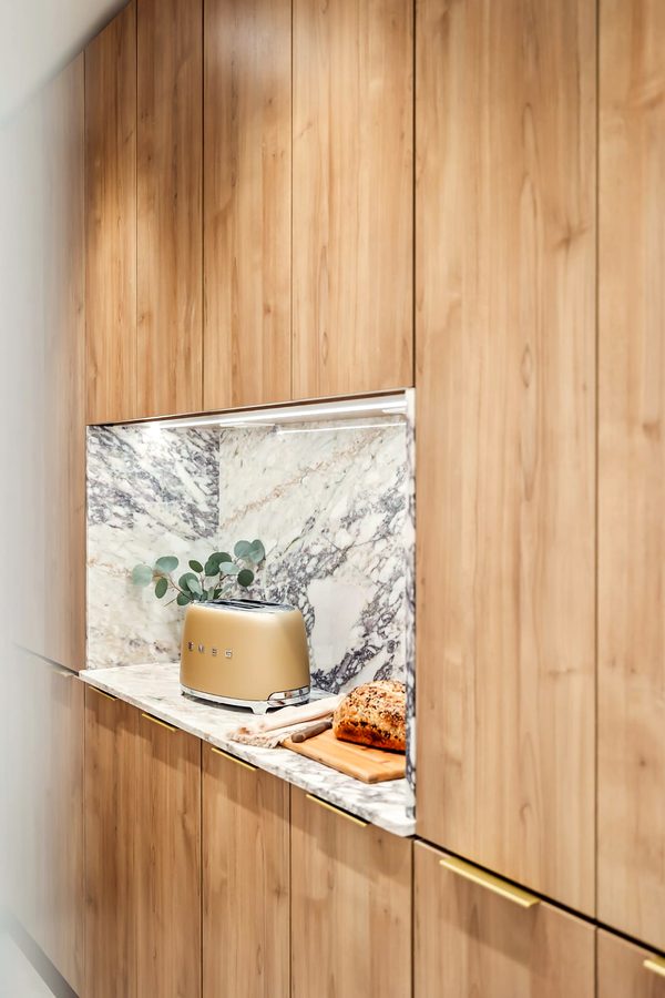 Full-height oak cabinetry with a lit marble niche